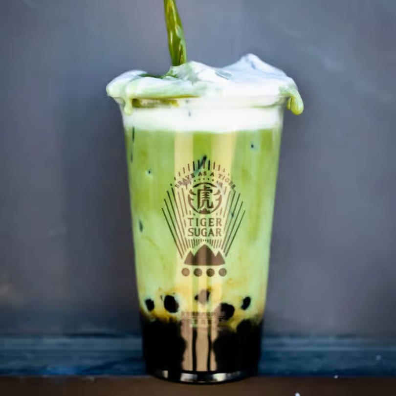 Matcha boba tea with cream foam and a Tiger Sugar logo on the cup.